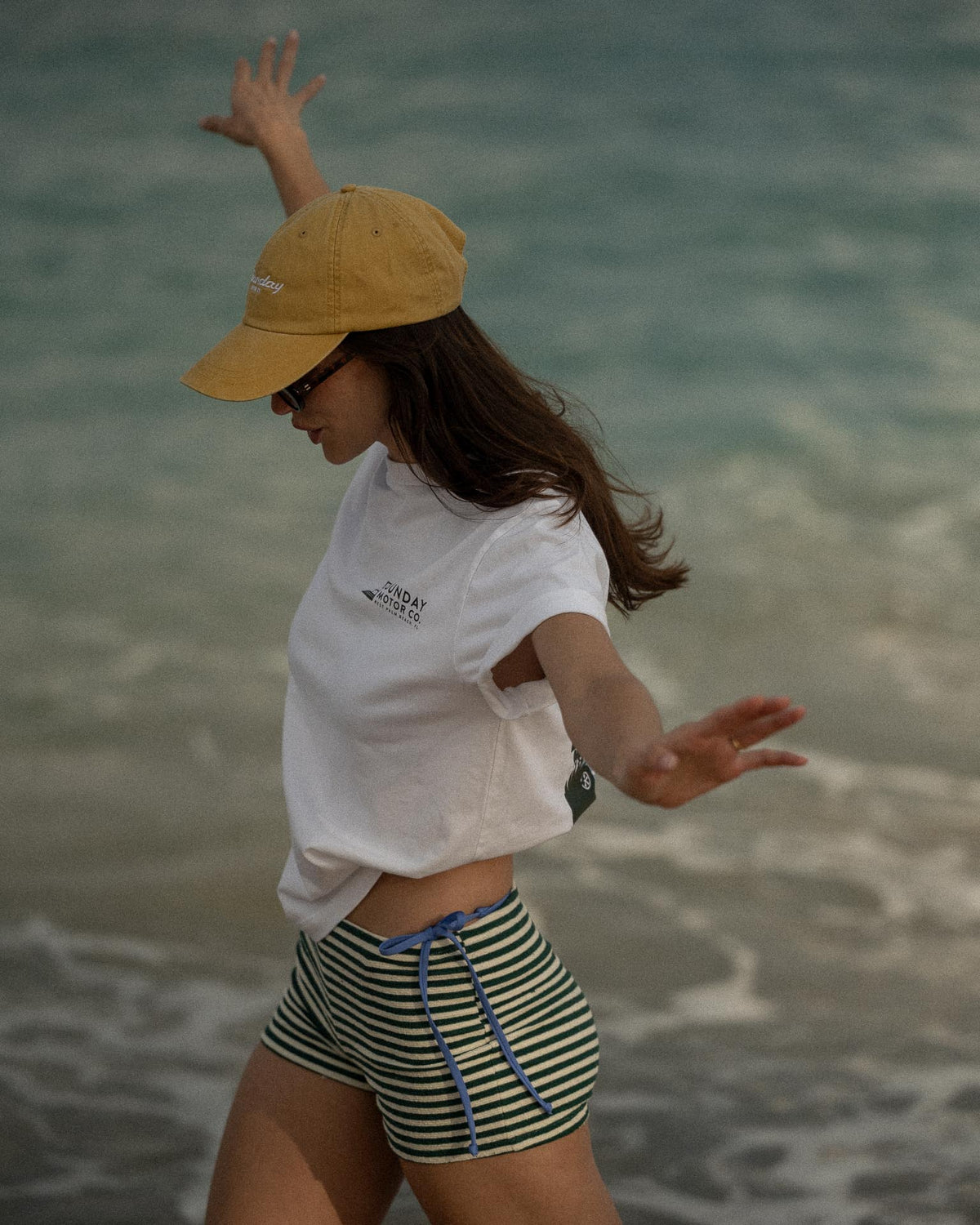 Person wearing a yellow cap and white shirt with ocean in the background
